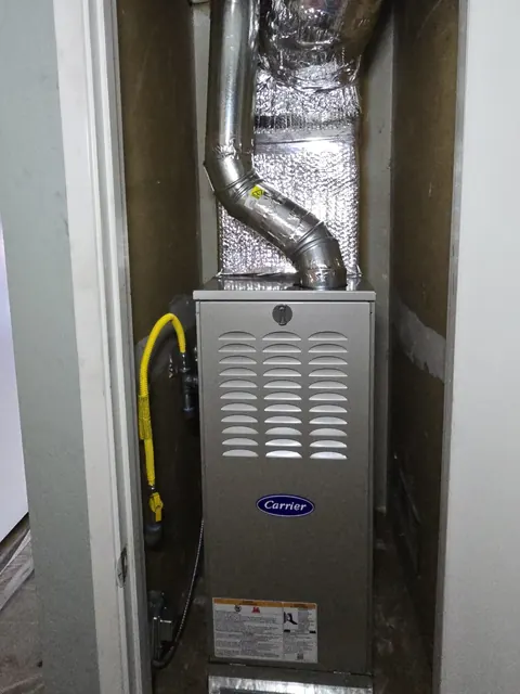 A new Carrier gas furnace fitted in a hall closet with a yellow gas line