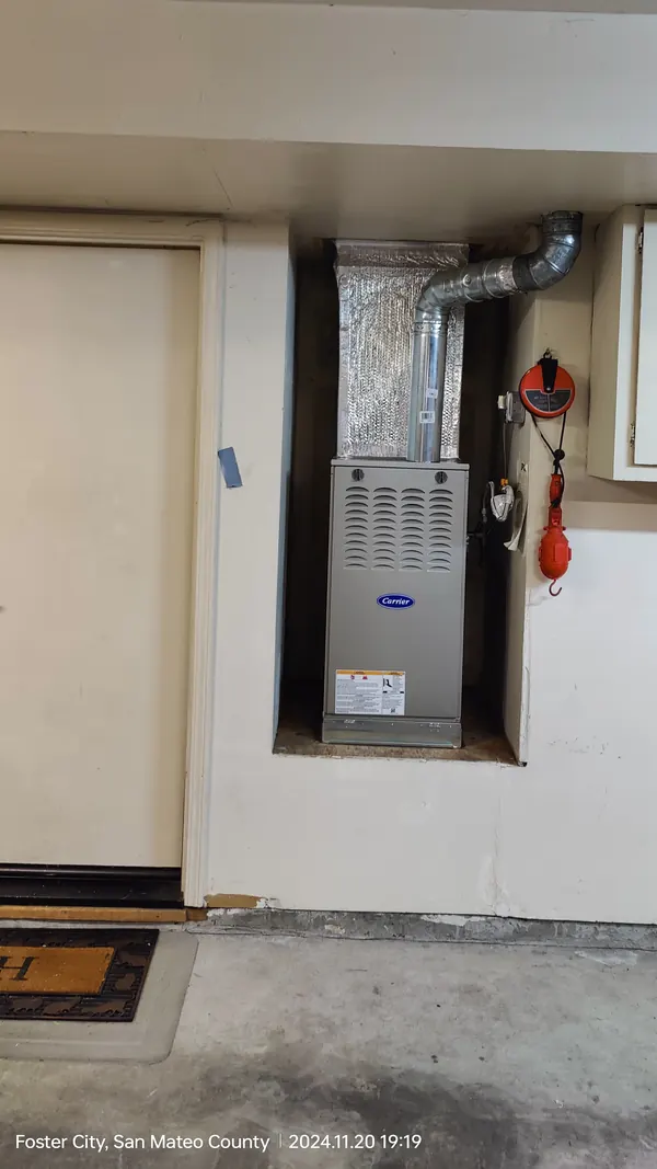 A wider view of the garage wall with the new Carrier furnace in its alcove and the floor in front of it cleared