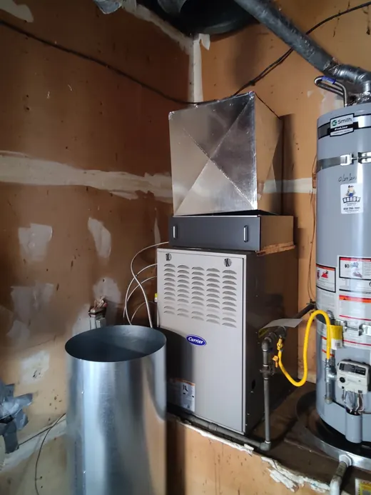 A new Carrier furnace beside a water heater with new duct above it