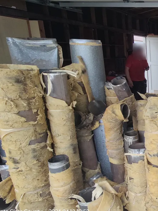 Old round ducts in yellowed insulation laid out across a garage floor